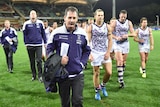 Coach Ross Lyon walks in front of some of his Fremantle Dockers players and fellow coaches on Adelaide Oval.