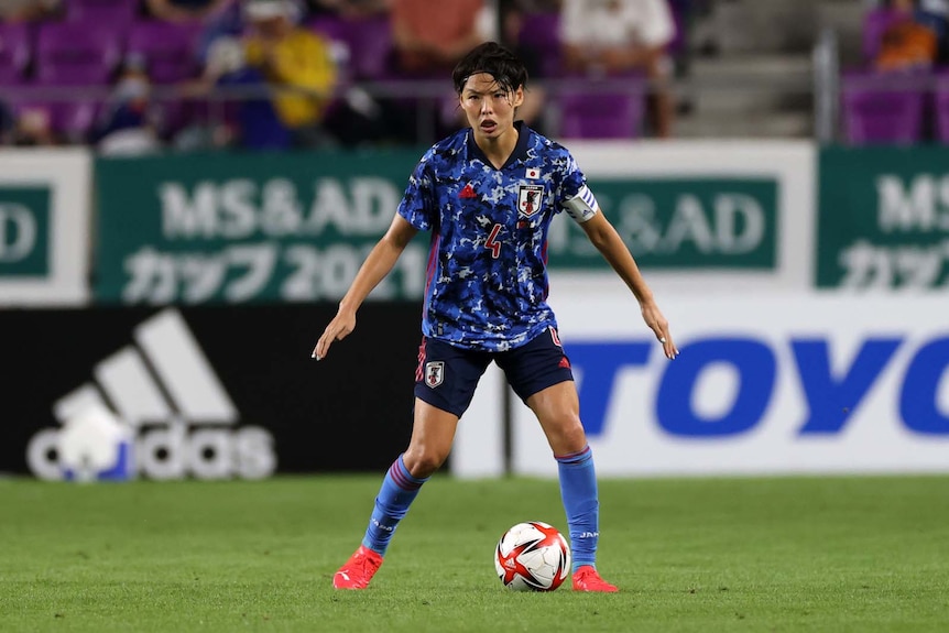 Japanese defender Saki Kumagai poised to pass the ball during a match.