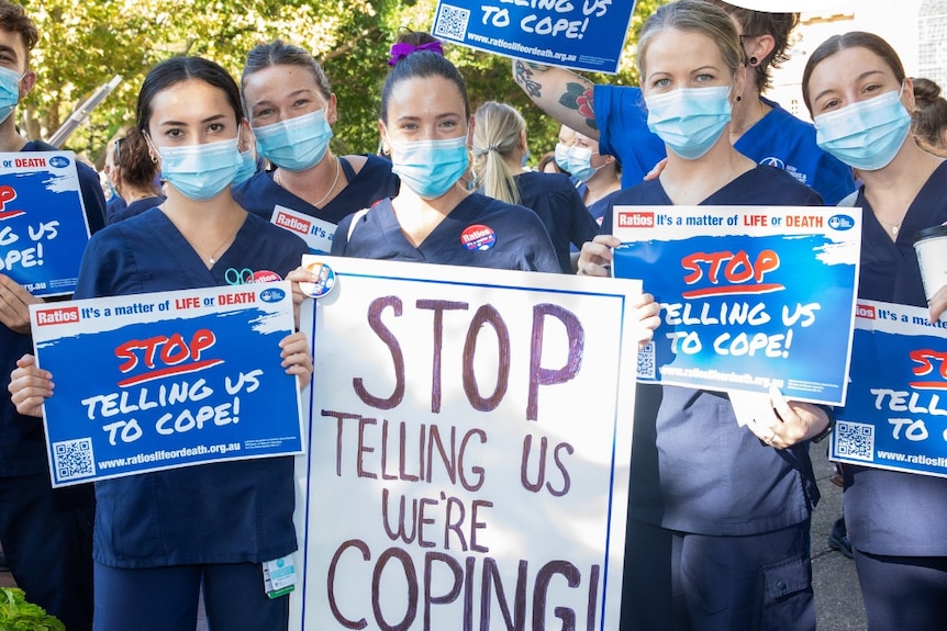 nurses holding protest signs at a rally
