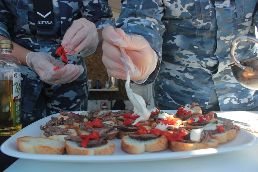 Air force recruits wearing rubber gloves serving food, close up image.