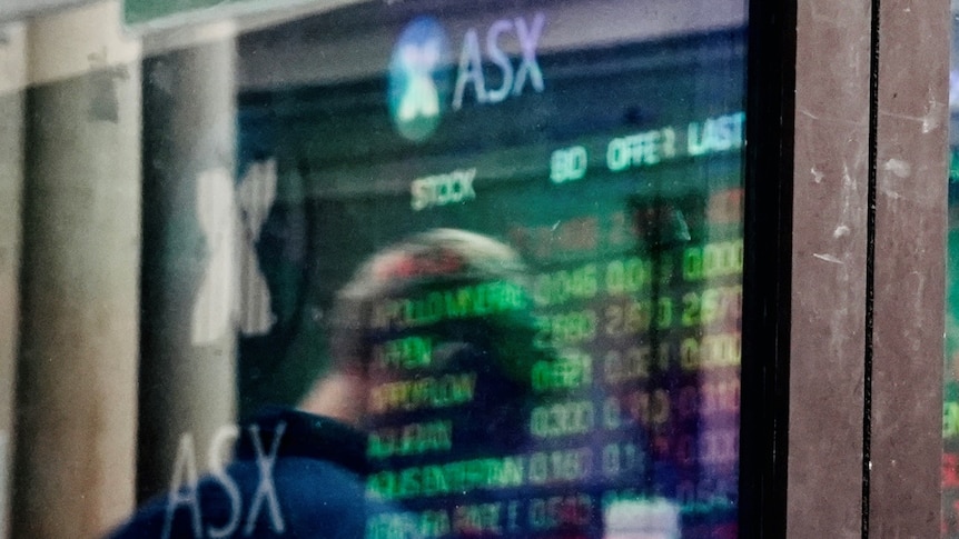 A man looks at a share price board outside the ASX in Sydney.