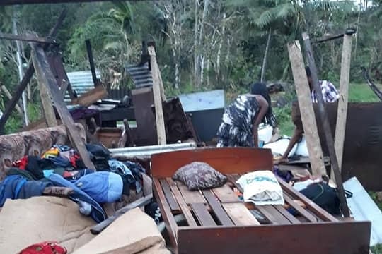 Two people sift through the wreckage of a home in Fiji.