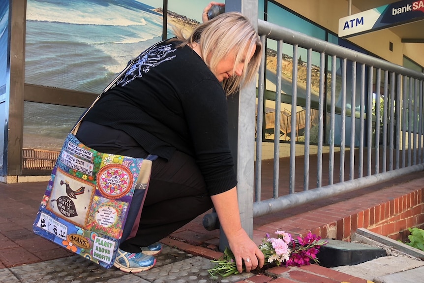 Woman leaving flowers at scene of Colonnades murder