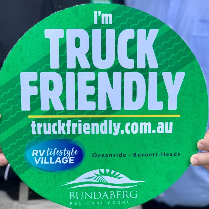 A large green sticker with the words "I'm Truck Friendly" is held towards the camera
