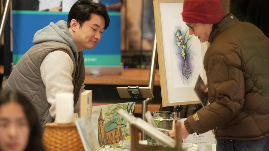 A man sells artwork at a stall