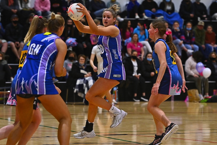 A netball player jumps to catch the ball.