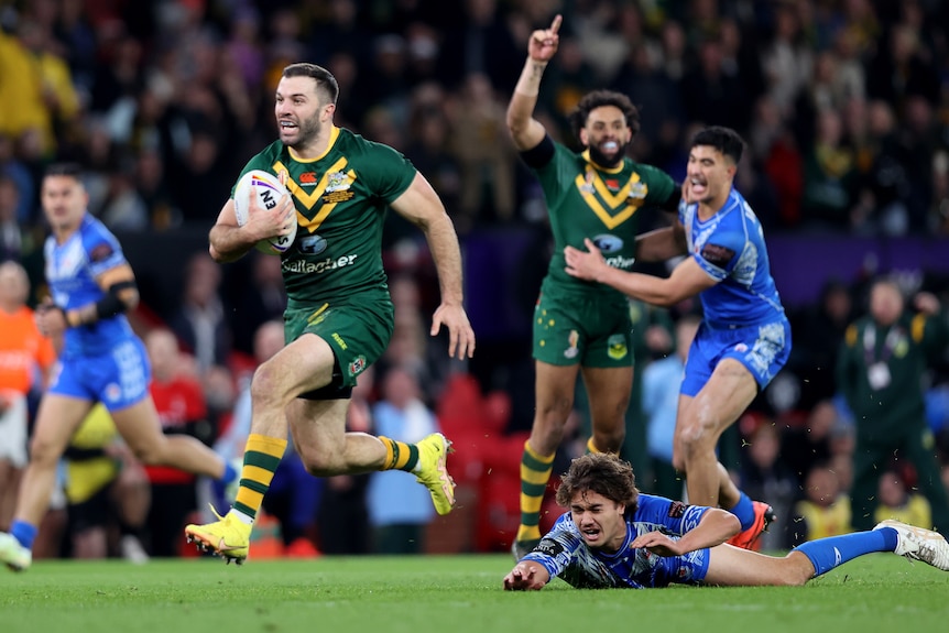 Un joueur de la ligue de rugby australienne court pour marquer un essai alors qu'un défenseur samoan est allongé sur le sol.