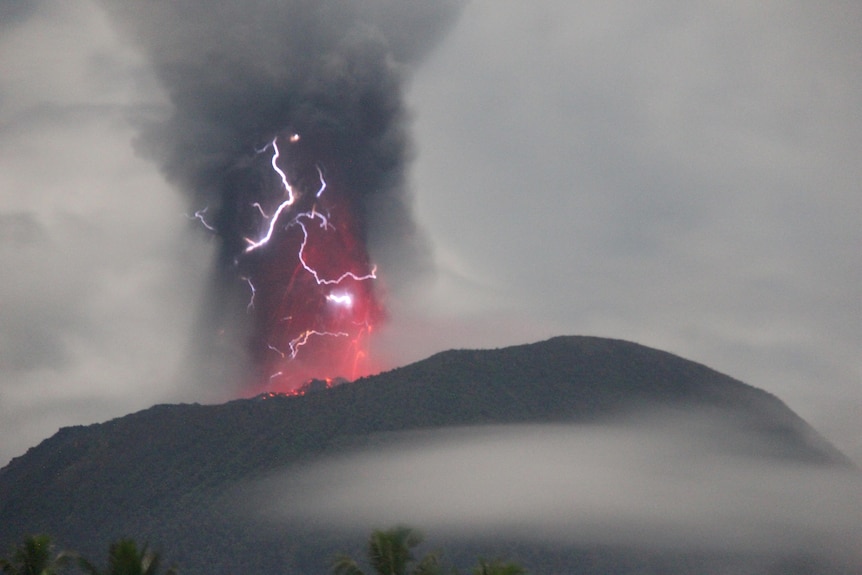 Mount Ibu erupting with lightening in the background.