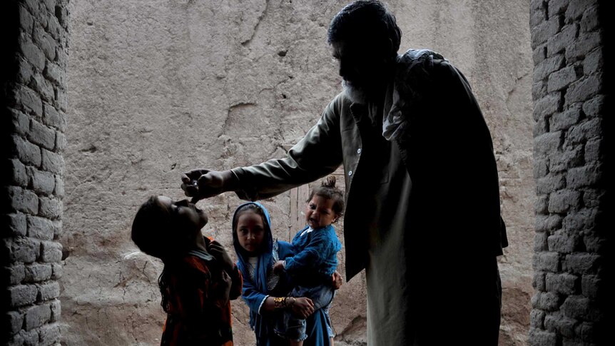 An Afghan health worker administers a polio vaccination to a child.