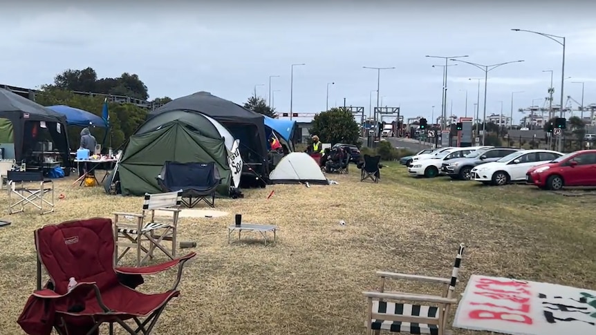 Camping chairs, tents are in view, and the dock to the right where trucks are parked is also in view.