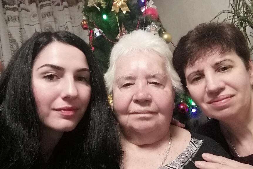 Three women posing for a photo in front of a Christmas tree