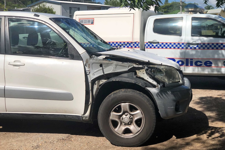 A small car with a damaged front right. A police van is behind it.