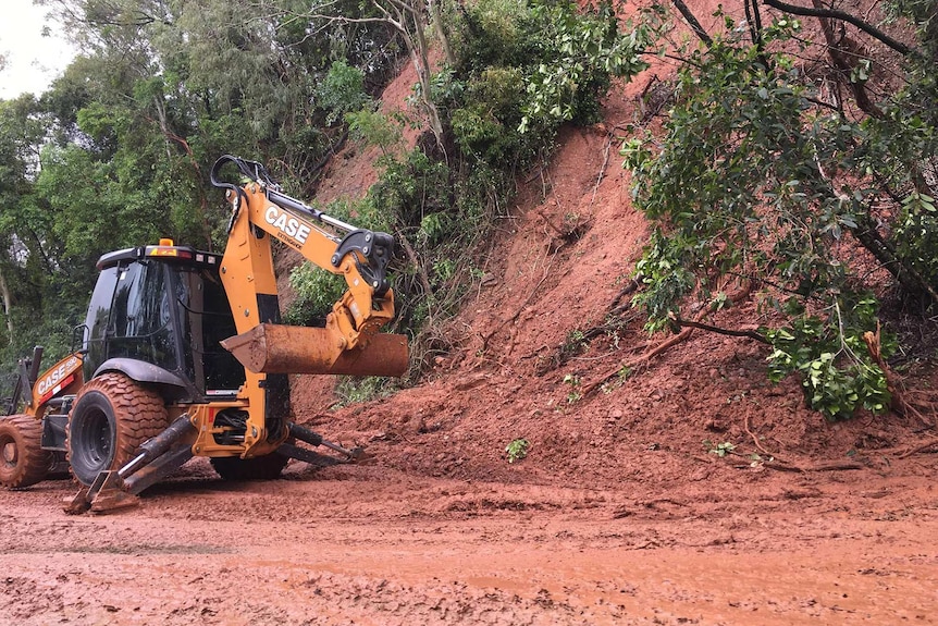 A digger next to the muddy remnants of a landslip.