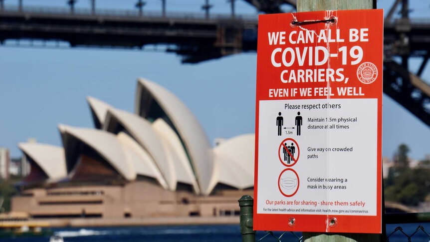 A COVID-19 sign with the Sydney Harbour Bridge and Opera House in the background during lockdown.