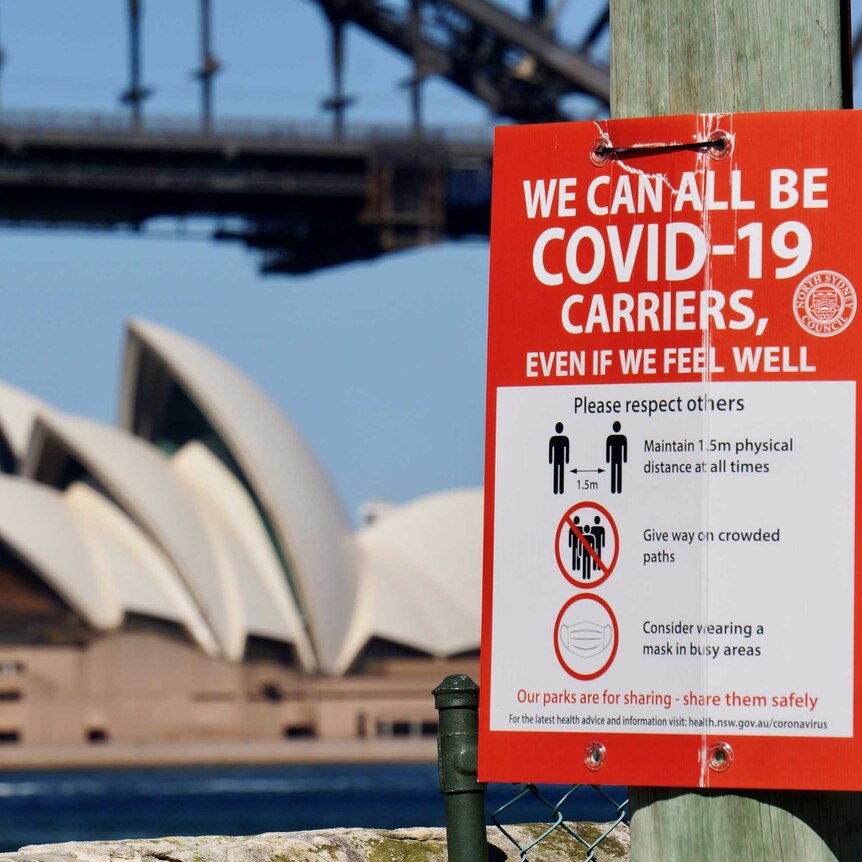 A COVID-19 sign with the Sydney Harbour Bridge and Opera House in the background during lockdown.