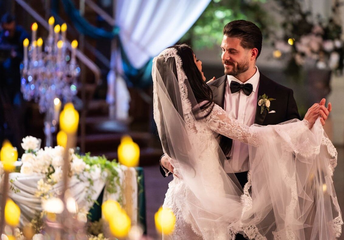 A bride and groom dancing in a candlelit room.