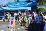 A group of protesters holding signs reading "I LOVE DMM" outside Dolphin Marine Magic in Coffs Harbour.