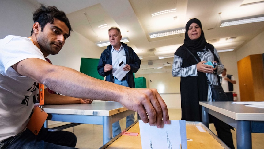 An man posts an election envelope in a polling station in Malmo