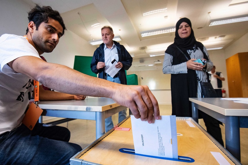 An man posts an election envelope in a polling station in Malmo