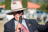 Close up of man in a big akubra holding a microphone to his lips