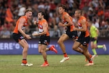 A group of Giants AFL players grin as they run back to the middle after a goal.
