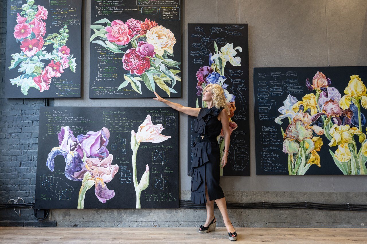 A woman pointing at several pictures on a wall.