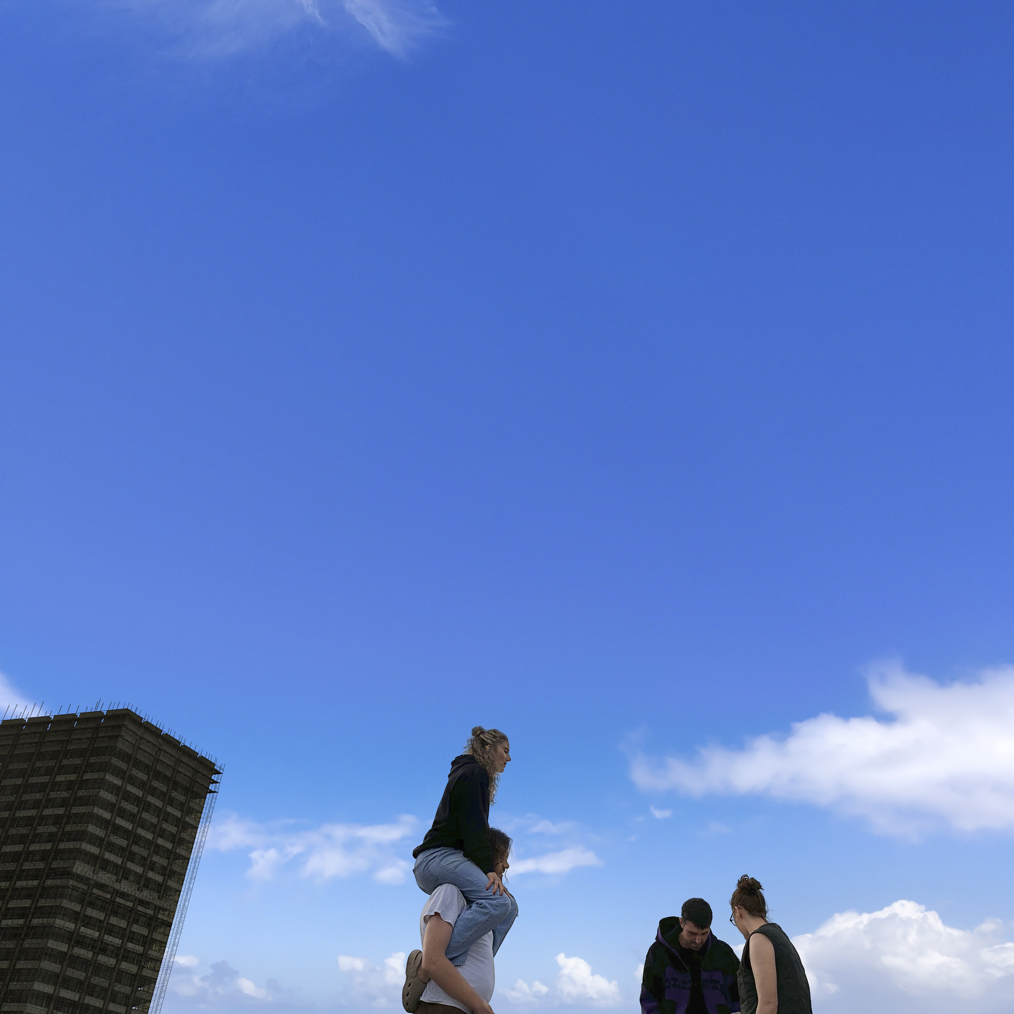 cover of Fred Again..'s 2024 album ten days: photo of blue sky with cropped building, person on someone's shoulders and friends