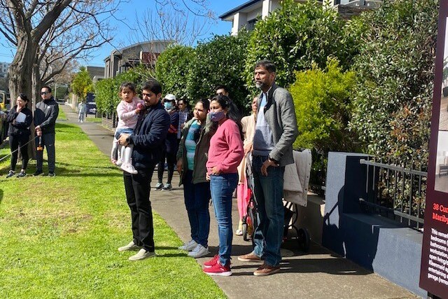A woman and her family watch on as bidding intensifies for a four bedroom house at auction in Melbourne on a sunny day 