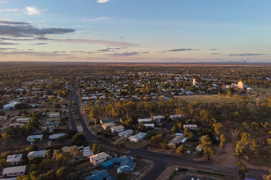 A drone shot of Clermont at sunset, a small regional town, white silos and mountains in distance.
