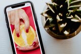 Image of phone showing fruit being handled by a female hand for a story on social media influencers sharing sex advice.