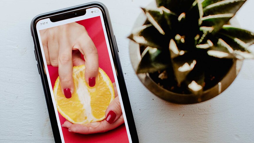 Image of phone showing fruit being handled by a female hand for a story on social media influencers sharing sex advice.