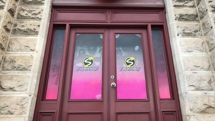 Wooden doors with pink signage saying Shadows