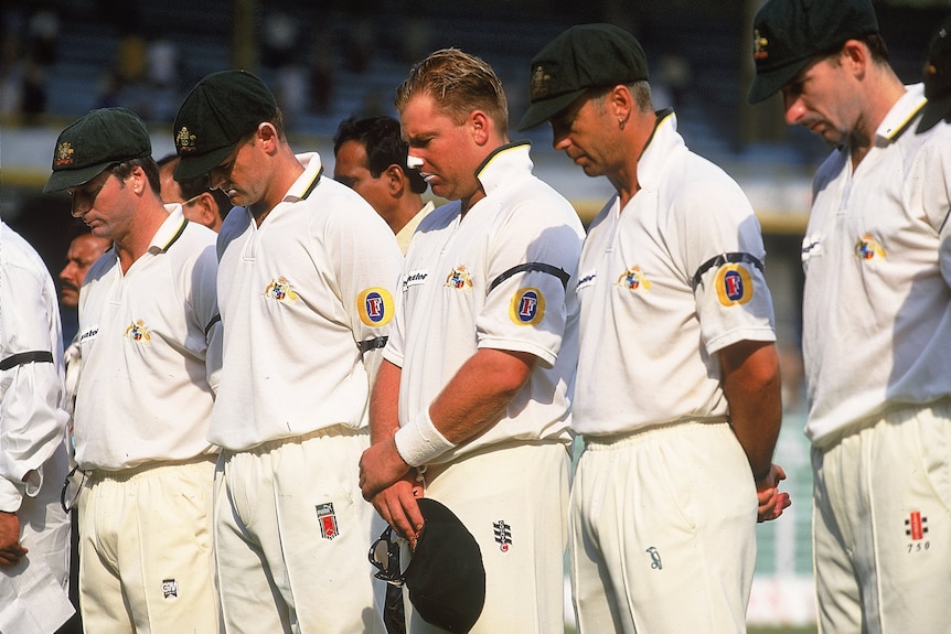 Men in whites bow their heads