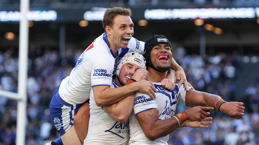 Three members of the NRL Canterbury Bulldogs celebrate scoring against the Newcastle Knights