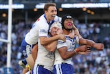 Three members of the NRL Canterbury Bulldogs celebrate scoring against the Newcastle Knights