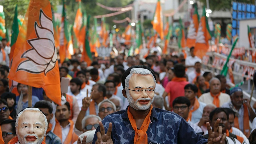 Two men wear masks that bear resemblance to Narendra Modi during a rally in support of India's PM.