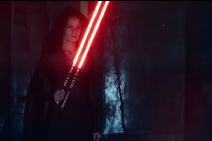 Daisy Ridley in a black robe with a red lightsaber