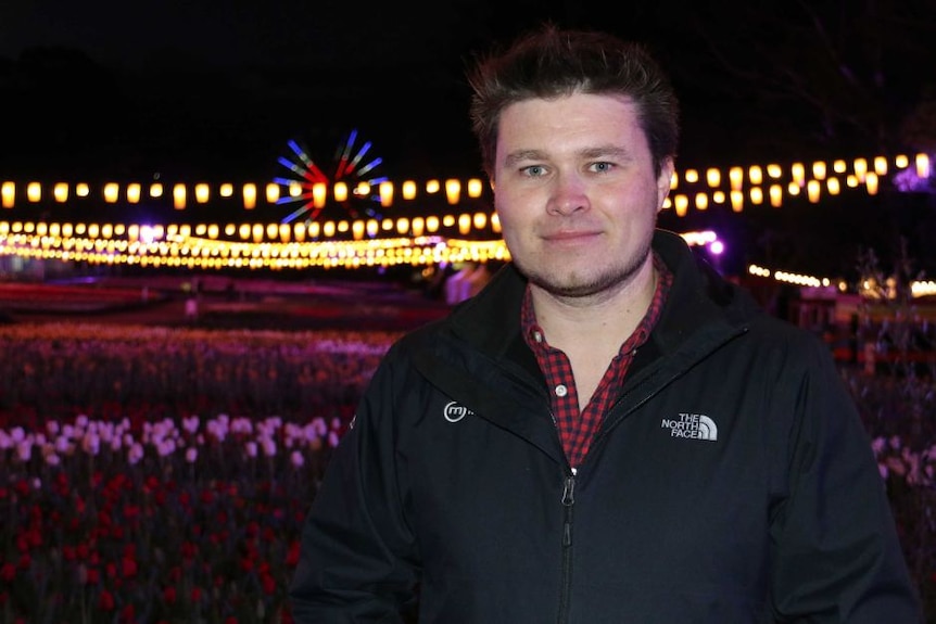 Richard Neville standing in front of a field of flowers and colourful lights