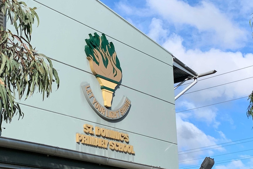 An emblem on the side of a green buliding saying St Dominic's Primary School