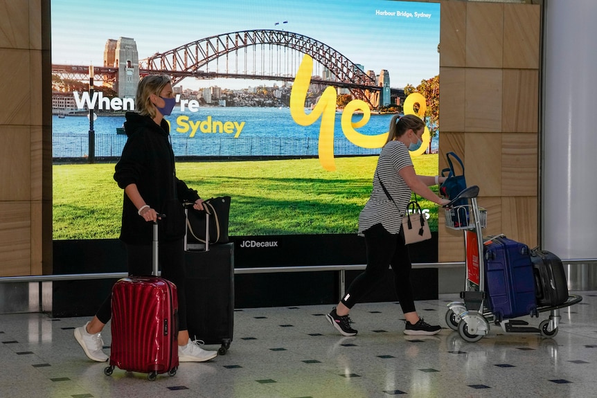 Two women push their luggage while arriving at Sydney airport