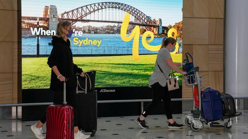 Two women push their luggage while arriving at Sydney airport