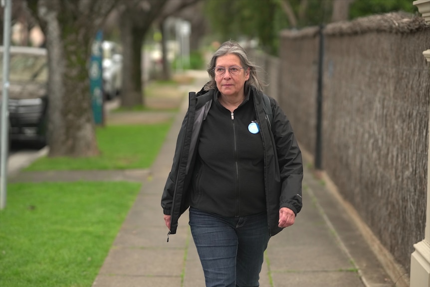 A woman wearing glasses in a dark top walking down a footpath