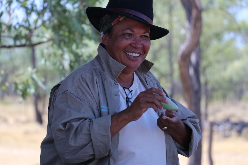Woman in the outback heat smiling while holding bush food 