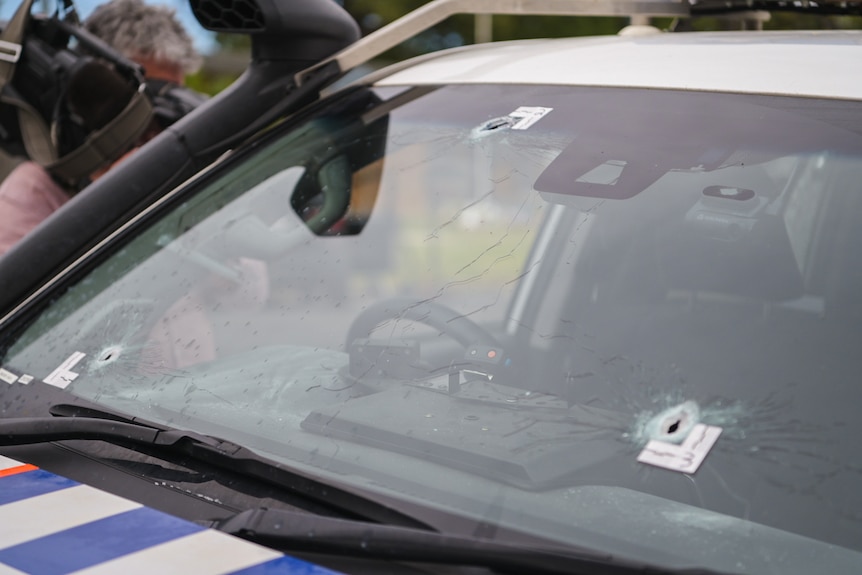 Bullet holes through the front windscreen of a police vehicle.
