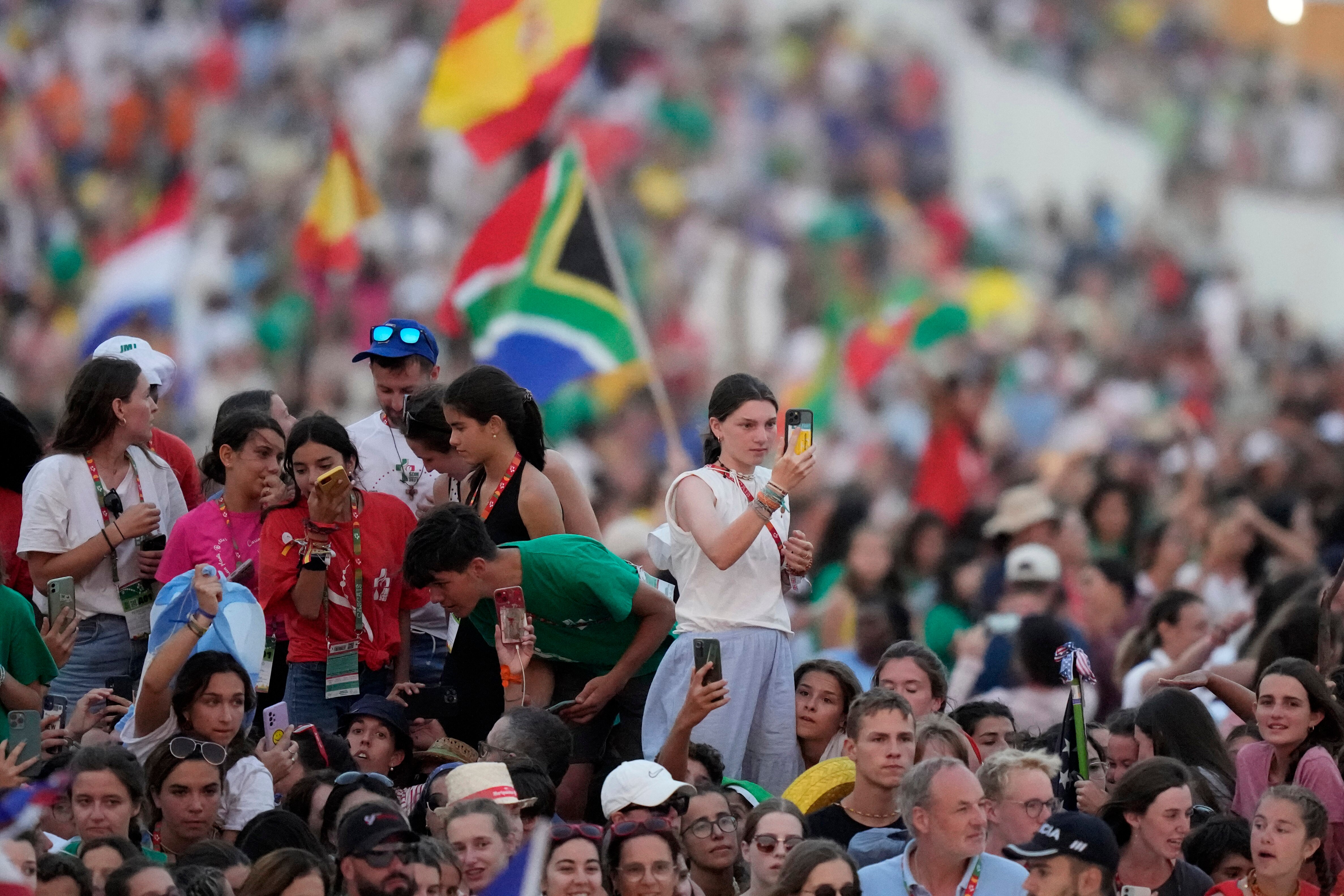 Some people sticking above a crowd, holding out mobile phones in their hands.