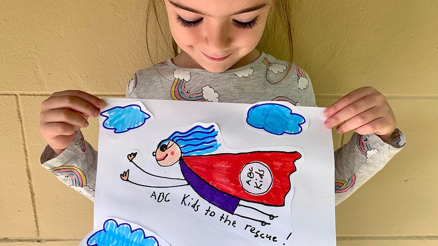Girl holding up artwork with caped woman and text 'ABC Kids to the Rescue!'