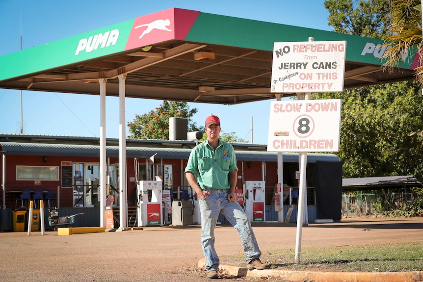 a man standing in front of a petrol station.