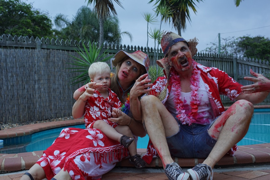 Mum, dad and baby dressed in Hawaiian shirts and smeared with fake blood