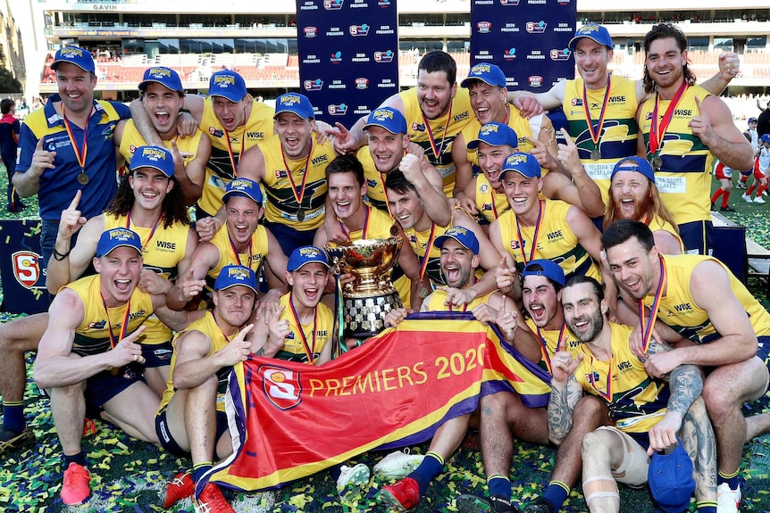 Footballs players covered in ticker tape celebrate on an oval.