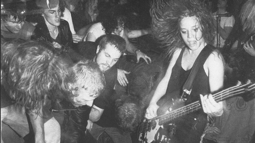 L7's Jennifer Finch playing live to a rowdy crowd on the back cover of the 'Shove' 7" single